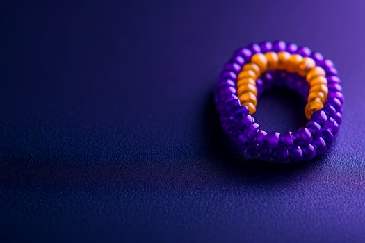 Purple, orange beaded ring on dark background, closeup, craft photo