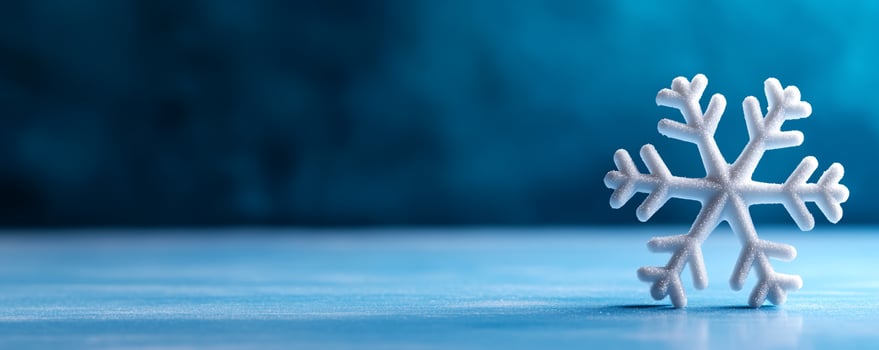 White snowflake on blue surface, blurred background, winter holiday card photo