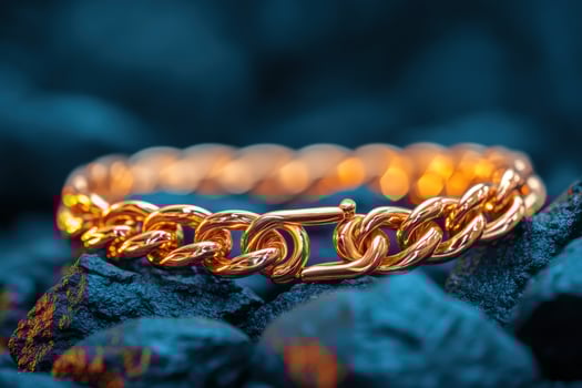 Gold chain bracelet on dark rocks, glowing background photo