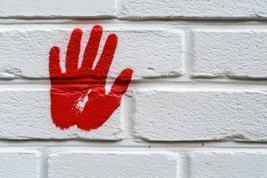 Red handprint on white brick wall, urban background, protest art photo