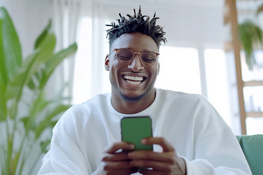 Smiling man uses mobile phone with green screen indoors photo