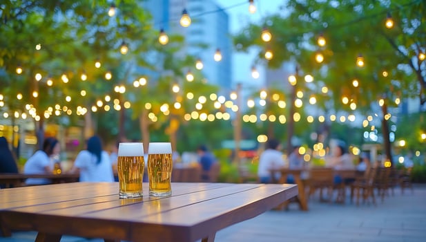 Beer glass at outdoor restaurant on wooden table with string lights photo