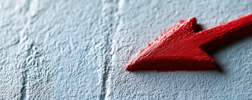 Red arrow points down on textured surface background, wood grain. Business concept photo