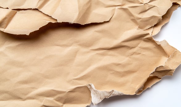 Textured tan crumpled paper with rough edges on white background for design elements photo