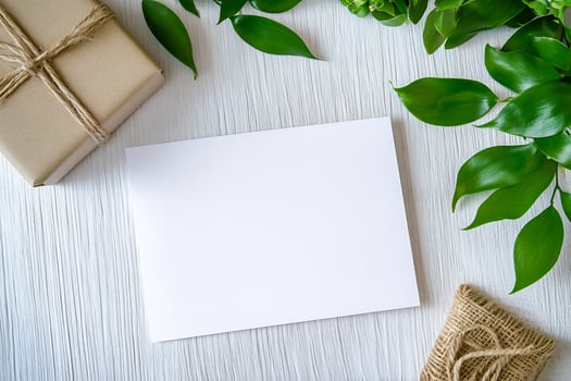 Blank card on white wood with gift and green leaves copy space photo