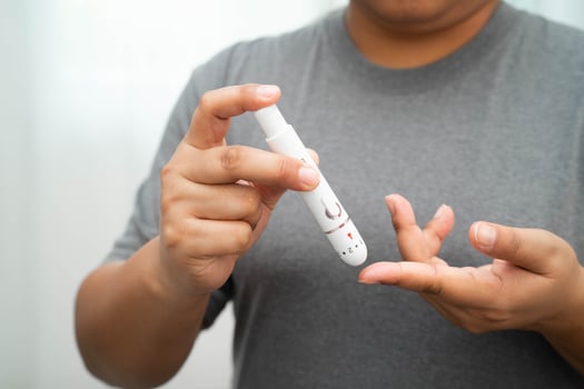 Asian woman self testing to check blood sugar level diabetes by digital lancet on finger at home. photo