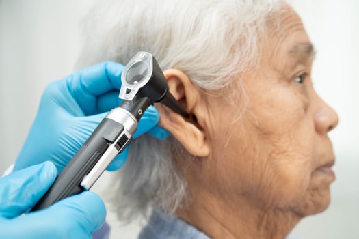 Otolaryngologist or ENT physician doctor examining senior patient ear with otoscope photo