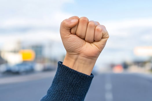 Raised fist symbolizing protest and solidarity against urban backdrop photo