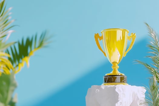 Golden trophy on a white pedestal with tropical palm leaves against blue backdrop concept photo