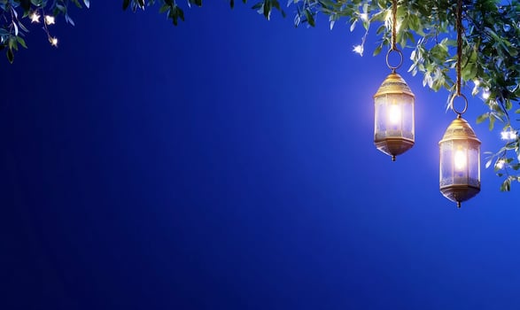 Illuminated lanterns hanging from tree branches against blue background photo
