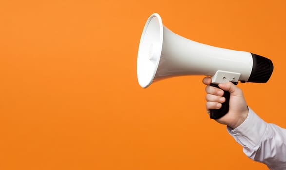 Hand holding megaphone for announcement on orange background communication concept photo