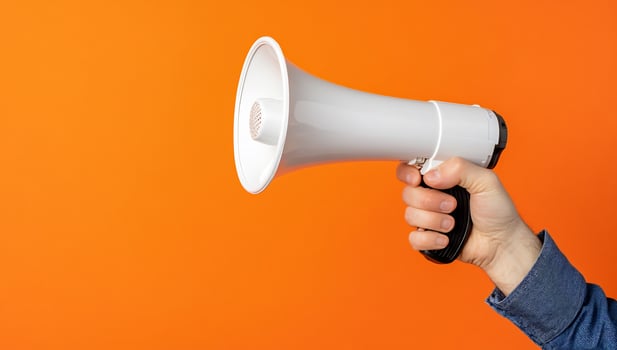 Hand holding megaphone against orange background communication concept photo