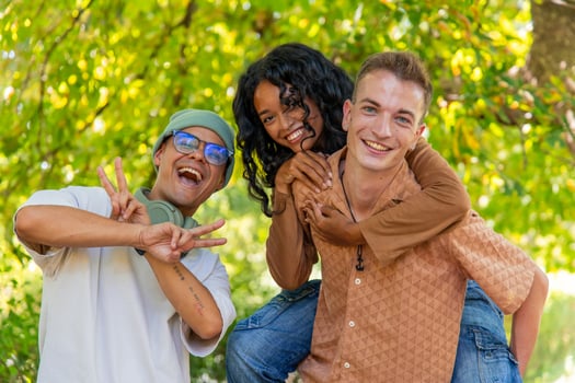 Happy multi-ethnic friends having fun piggybacking in a park photo
