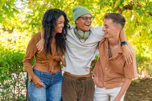 Happy multi-ethnic friends embracing and laughing together in a park photo