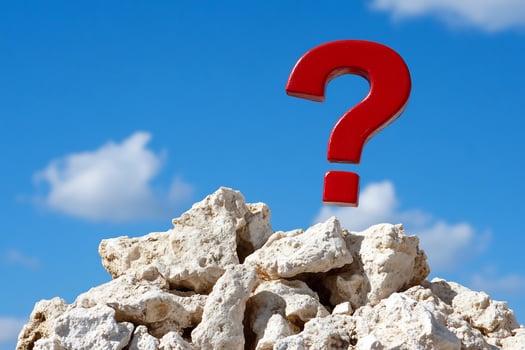 Red question mark above rocks against blue sky concept photo