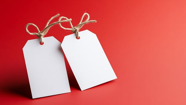 Blank white tags on red background with rustic twine for messaging and promotions photo