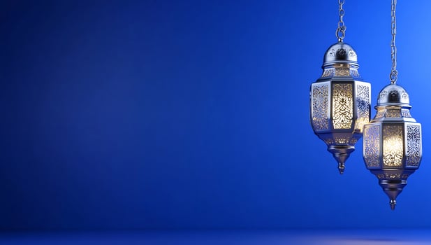 Decorative metal lanterns hanging on chains against blue background photo