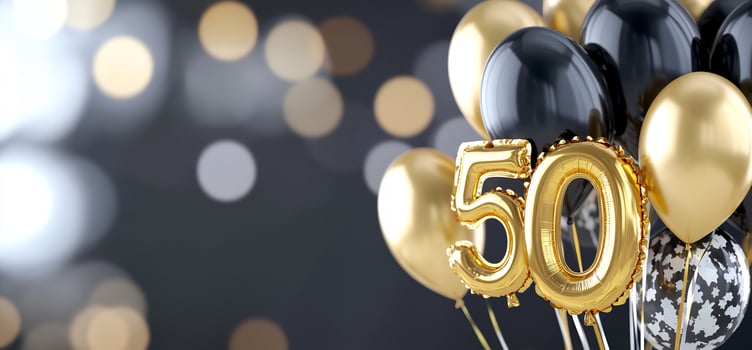 Celebratory fifty number balloons in gold and black on bokeh background for birthday anniversary or event photo