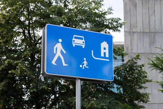 Blue traffic sign with white pictograms illustrating a pedestrian, car, playing child, and house, indicating a safe, quiet residential zone for shared community living photo