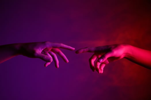Two hands reaching toward each other against a gradient purple and pink background, symbolizing connection. photo