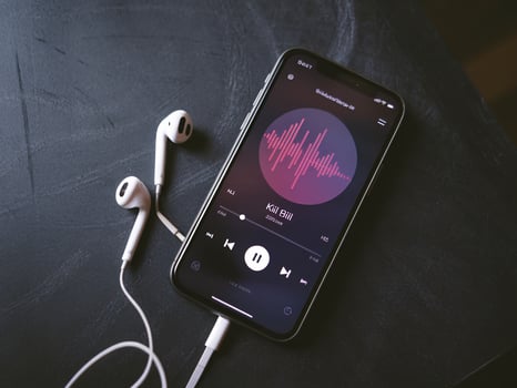 Close-up of a smartphone displaying a music app with earbuds beside it, creating a cozy vibe. photo