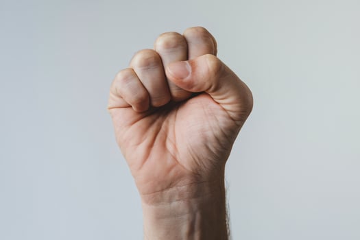 A close-up of a raised fist against a soft grey background, symbolizing strength and determination. photo