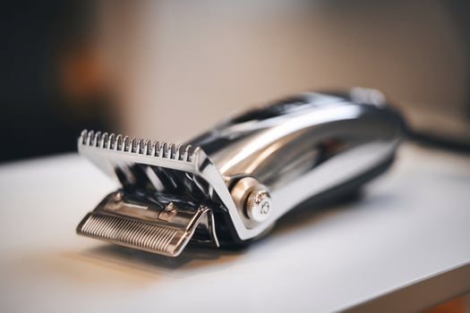 Close-up of a sleek silver hair clipper on a white surface, showcasing its fine cutting blade. photo