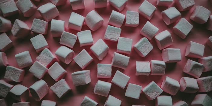 Colorful marshmallows scattered on a pink surface, creating a playful and sweet atmosphere. photo