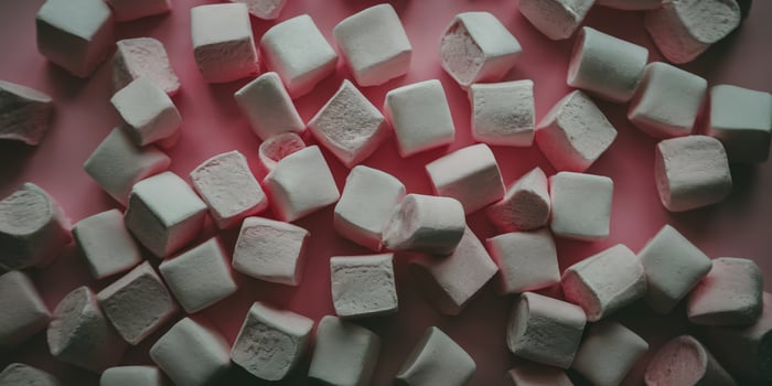 Sweet, fluffy pink and white marshmallows scattered on a soft pink background. photo