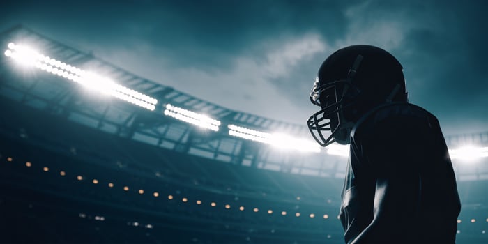 Silhouetted football player in helmet, ready for action under stadium lights. photo