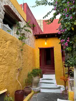 Mediterranean-style courtyard with yellow and red walls, potted plants, blooming flowers, and a cozy stone staircase, showcasing elegance and cultural beauty, concept of travel, lifestyle, heritage photo