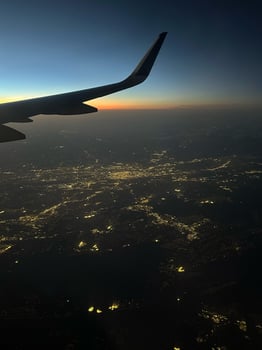 Aerial view of an airplane wing silhouetted against a twilight sky with illuminated city lights sprawling below, showcasing travel and scenic beauty, concept of adventure, aviation, lifestyle photo