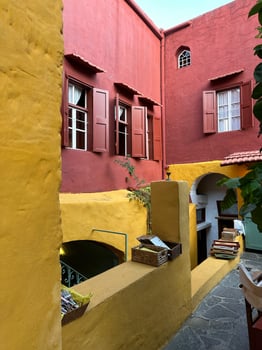 Vibrant red and yellow stucco buildings in a Mediterranean alley with rustic windows, arched doorways, and outdoor decor, showcasing architectural charm and cultural elegance, concept of travel photo