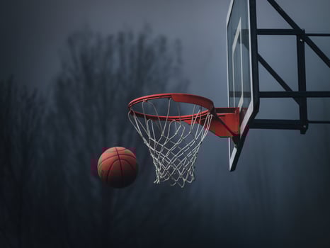 Dynamic shot of a basketball soaring toward a hoop in a misty, atmospheric setting. photo