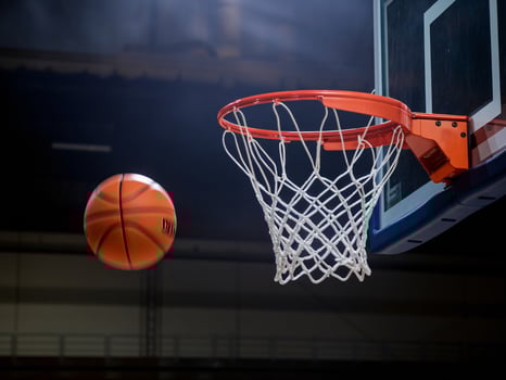 An action shot of a basketball about to enter a hoop, showcasing excitement in a gym setting. photo