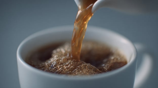 A luminous cascade of ebony coffee flows into a porcelain cup, celebrating Caffeine Awareness Month and International Coffee Day photo