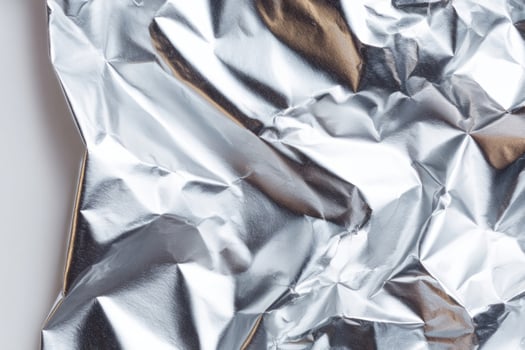 Crumpled silver foil resembling lunar landscapes, evoking Earth Day reflections, futuristic packaging, and abstract chaos of eccentric gift wrapping photo