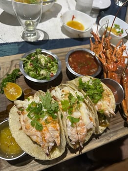 Close-up of gourmet lobster tacos topped with cilantro, served with fresh salsa, guacamole, and lemon wedges on a wooden board, showcasing elegance and vibrant flavors, concept of fine dining photo