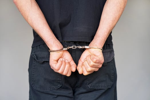 Criminal hands locked in handcuffs. Close-up view photo