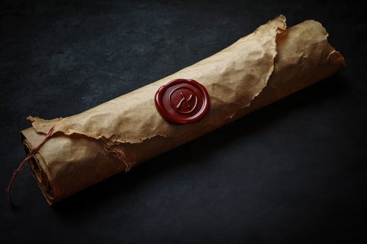 Ancient paper scroll rests sealed with a detailed red wax stamp on a dark background photo