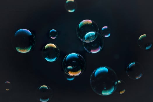Floating iridescent bubbles against dark background photo
