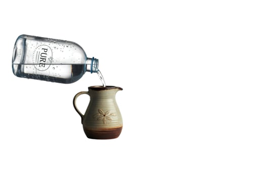 Pouring pure water from bottle into ceramic jug photo