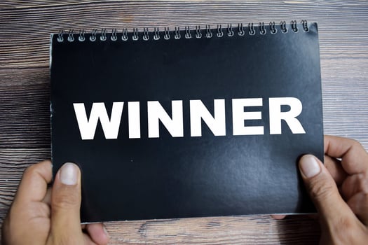 Concept of Winner - Individual or team who emerges achieve success in a competititon write on book isolated on Wooden Table. photo