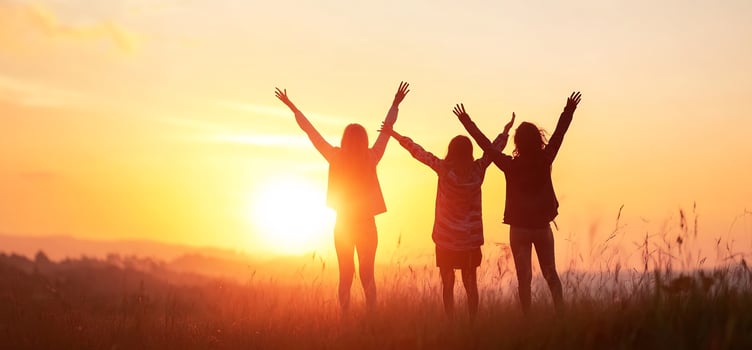 Silhouetted people celebrating success against a vibrant sunset landscape photo