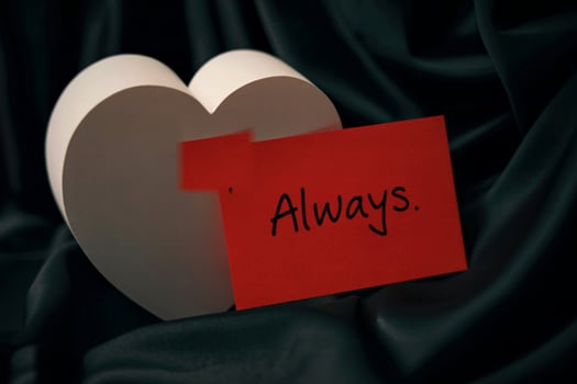 White heart with red card saying always on dark fabric photo