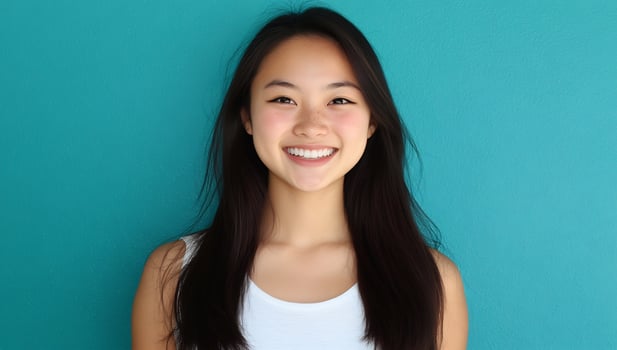 Smiling asian woman portrait against turquoise background headshot beauty and lifestyle theme photo