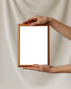 A person holding a wooden frame with a blank white background photo