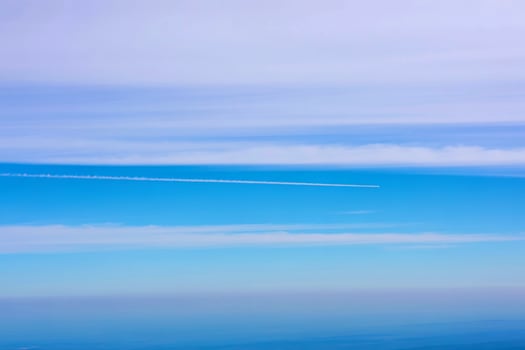 High altitude contrail over layered cloudscape photo