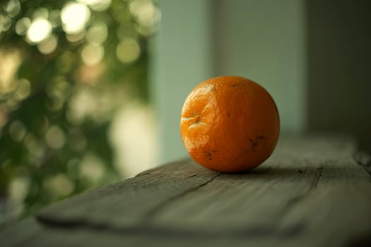 A single orange on a wooden table photo