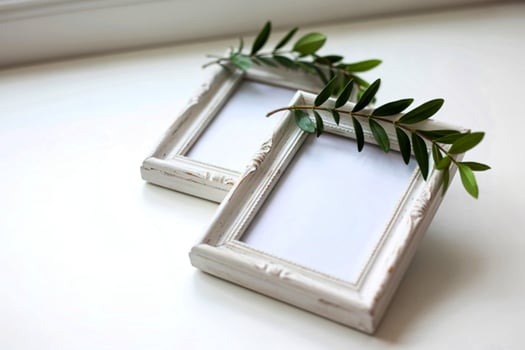 Two white picture frames with greenery photo